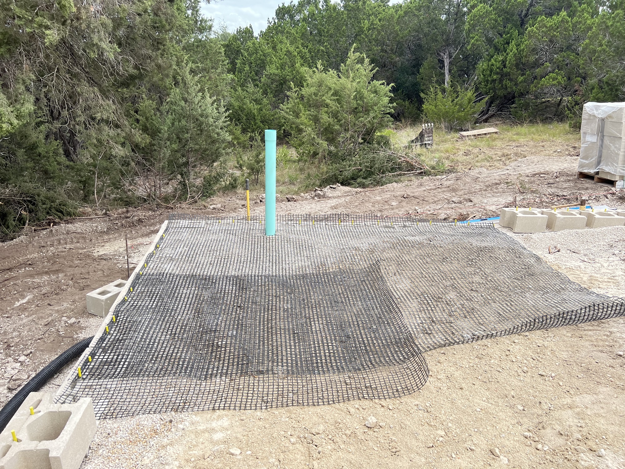 Laying the fabric strengthener for the block retaining wall that will be quite high upon finish