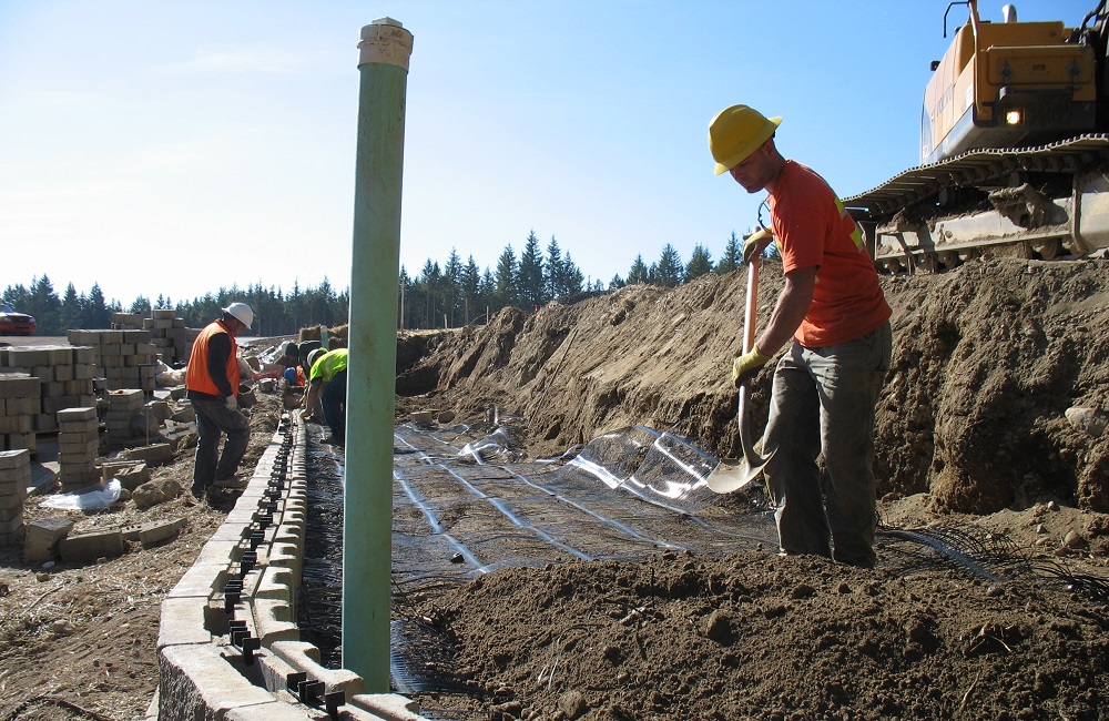 backfilling with dirt behind a block retaining wall