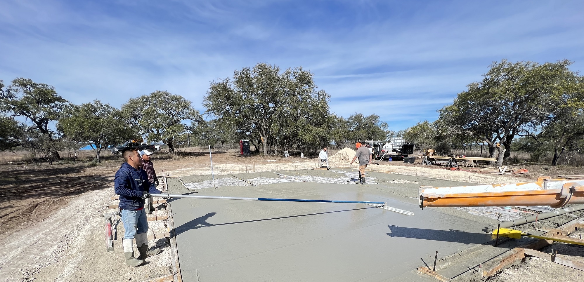 workers finishing a concrete foundation making it smooth for the floor