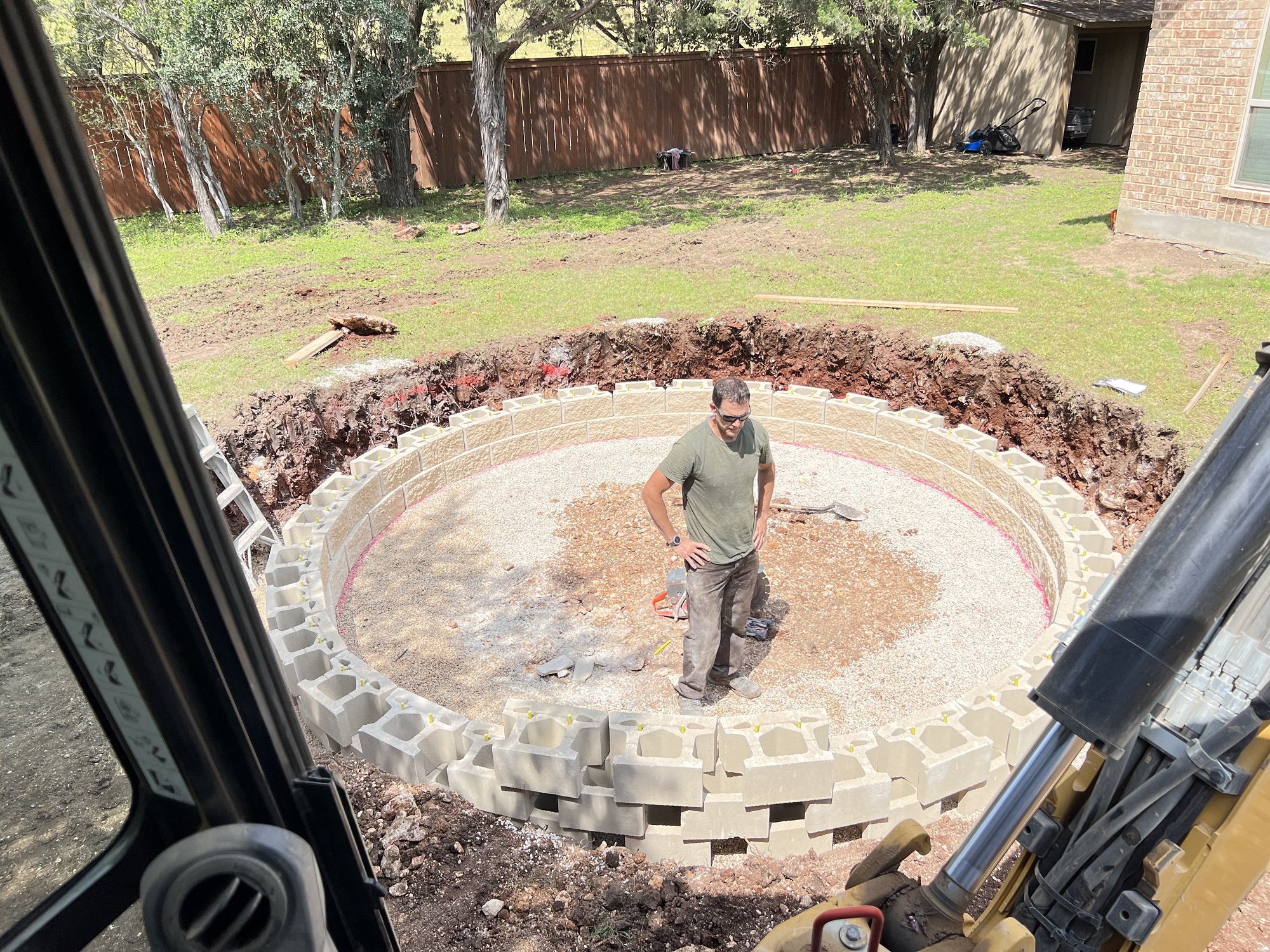 worker building a block retaining wall for sunken trampoline