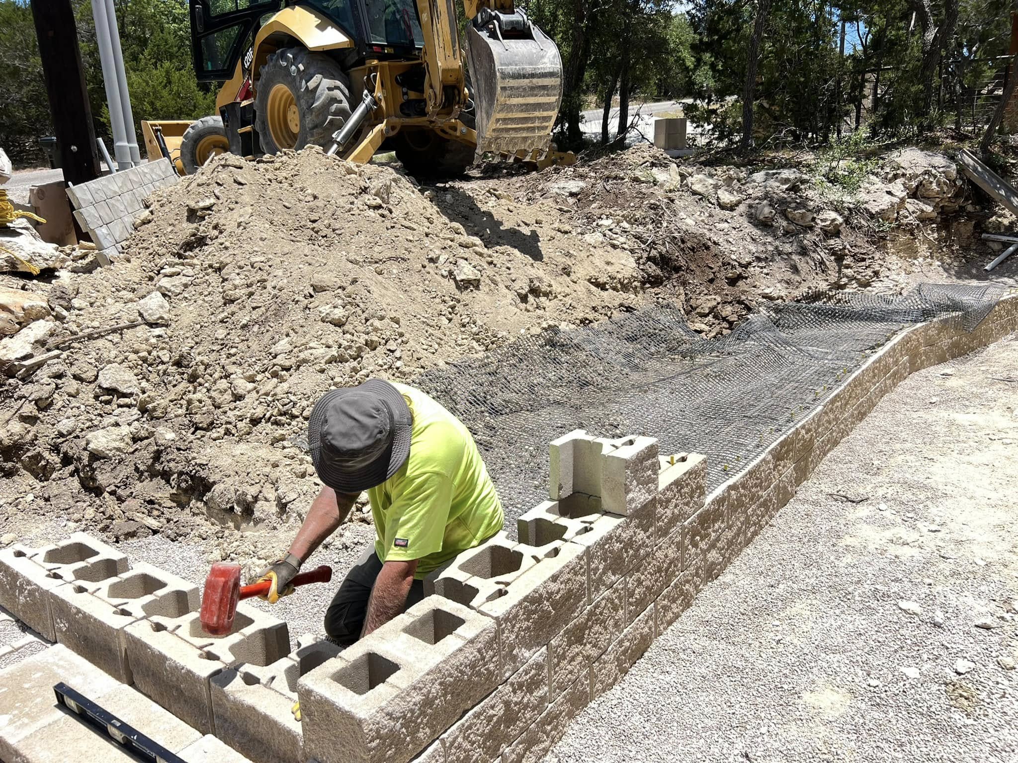 worker putting the capstones on a block retaining wall